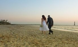 Bride and Groom hold hands on the beach