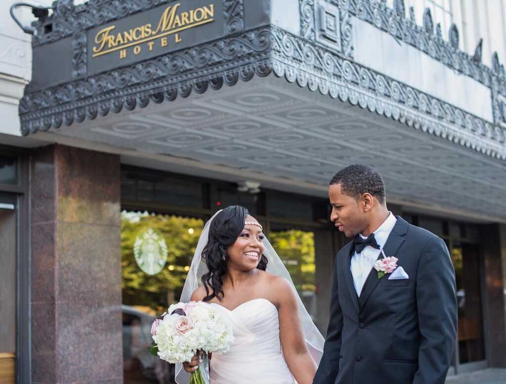 A happily married couple walking out of the Francis Marion Hotel after a beautiful Charleston, SC, wedding.